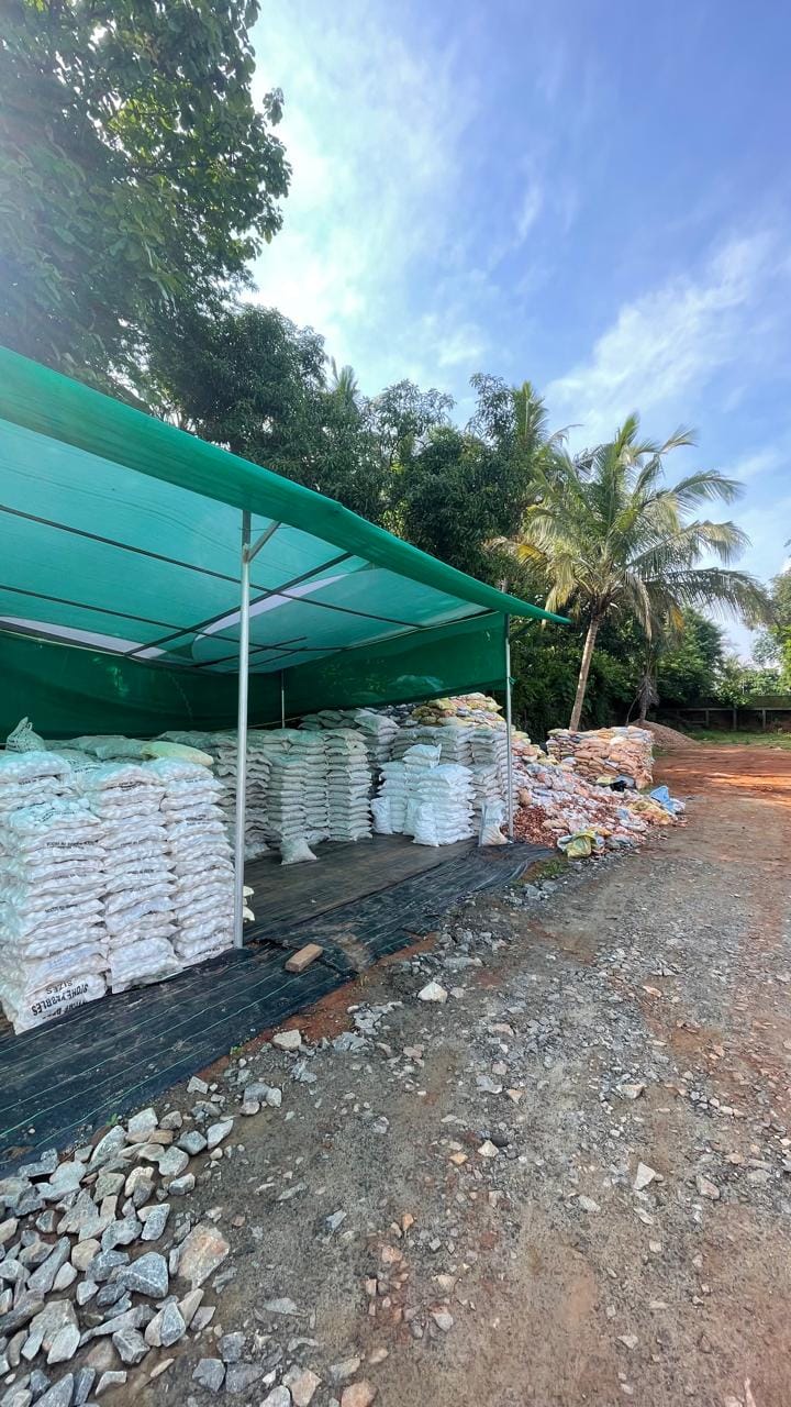 Stacked woven bags of landscape pebbles under green UV-resistant shade sails in Mannuthy, Thrissur