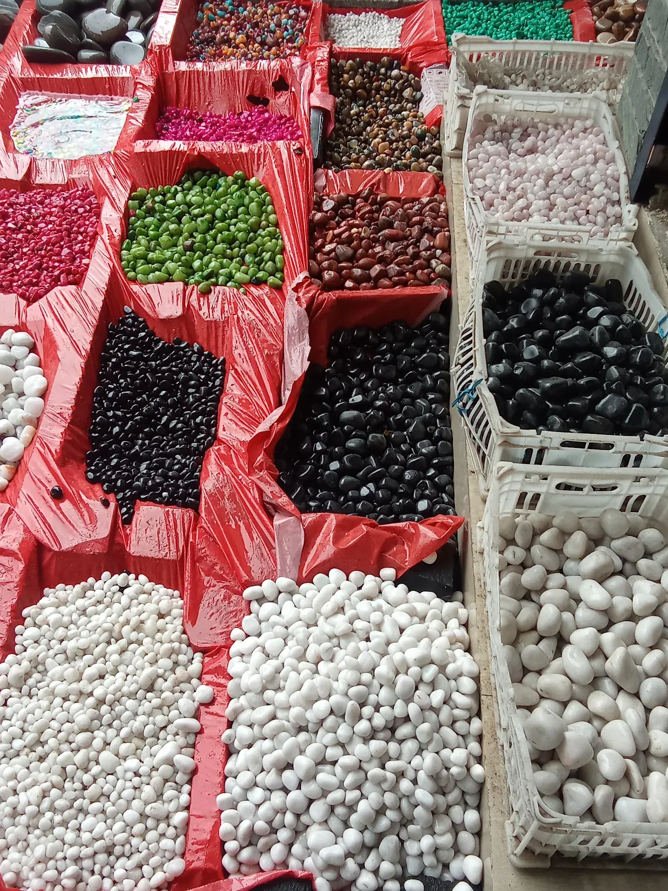 Sorted bins of high-gloss colored landscaping pebbles